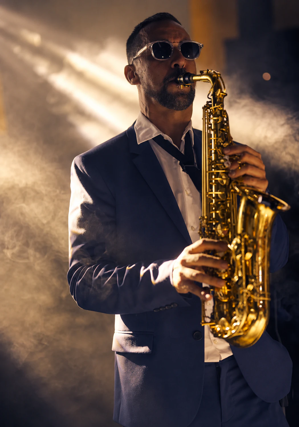 Tom Sax au saxophone sous une lumière dorée scénique