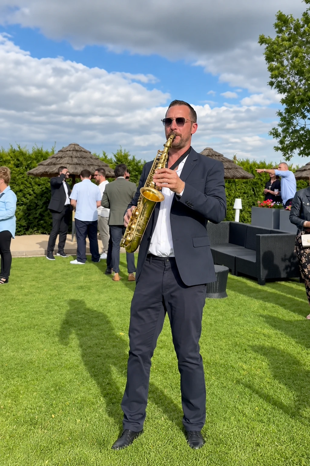 Tom Sax en prestation au cocktail dans un jardin ensoleillé